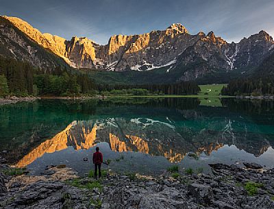 Tourist looking the Fusine lake and Mangart mountain group at sunset, Tarvisio, Julian alps, Friuli Venezia Giulia, Italy, Europe